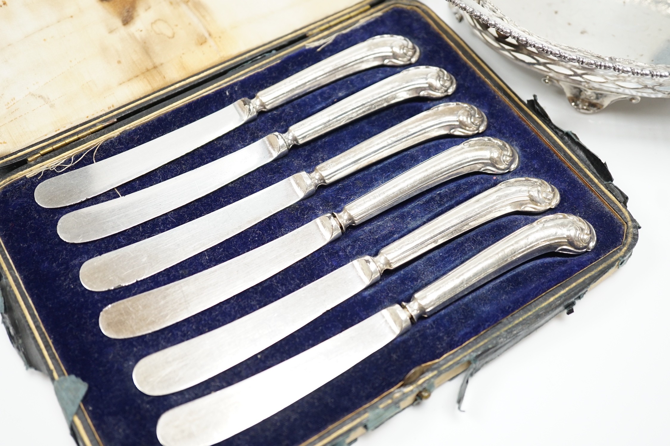 A George V pierced silver oval bowl, 21cm, London, 1912, 5.5oz and a cased set of six silver pistol handled steel tea knives.